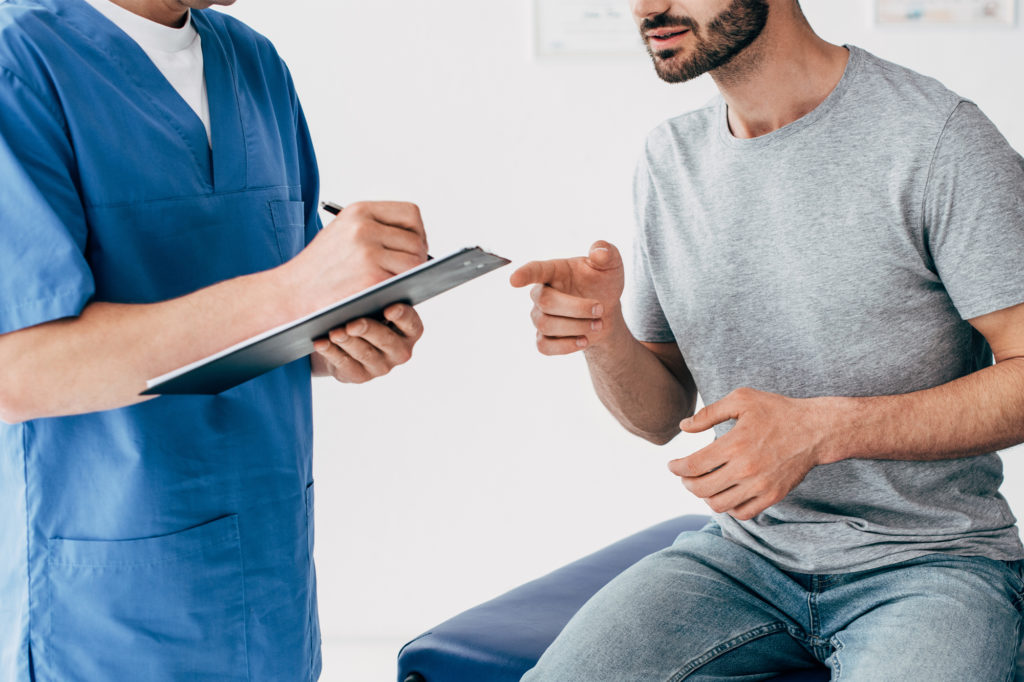 Doctor speaking with patient, holds clipboard in hand